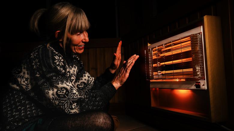 Woman warming up with space heater