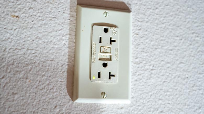 Electrical outlet installed upside down on white wall