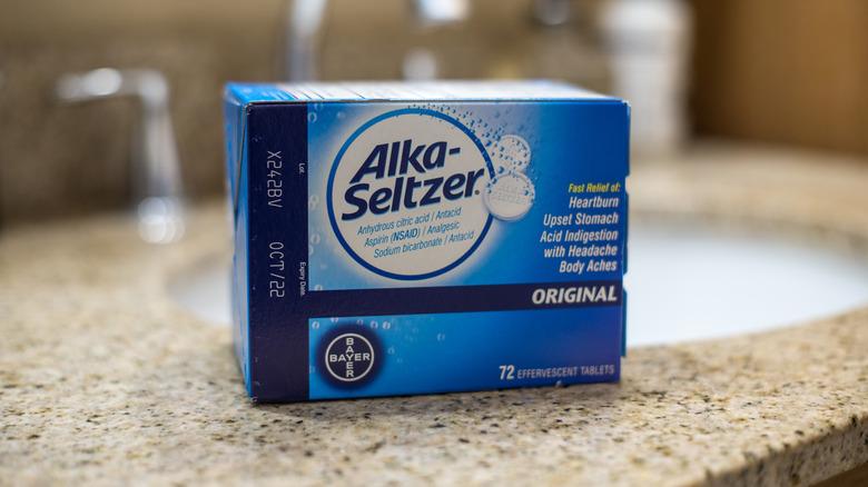 A box of Alka-Seltzer sitting on a bathroom counter next to the sink.