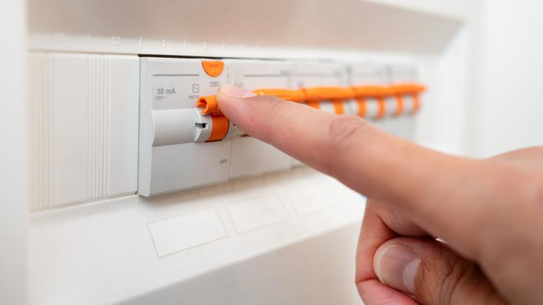 A set of electrical fuses are being inspected by a single finger.