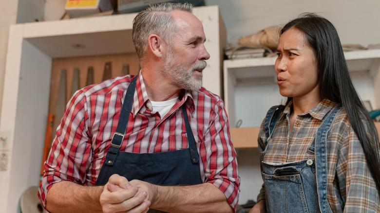 man and woman in woodworking aprons having a conversation