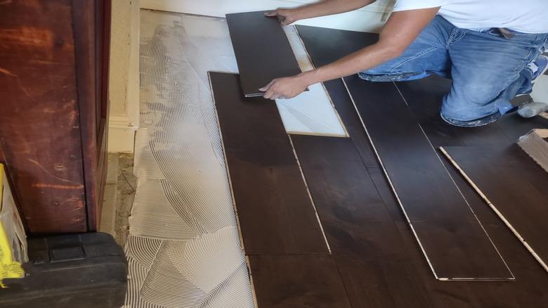 person shown up close installing engineered hardwood flooring