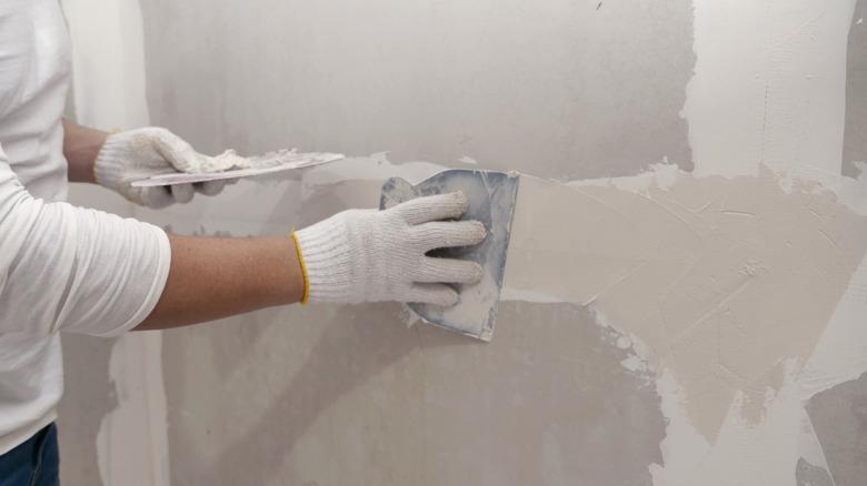 person spreading plaster on wall