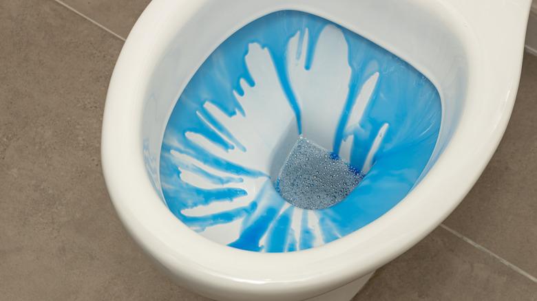 blue liquid fabric softener poured down a white toilet