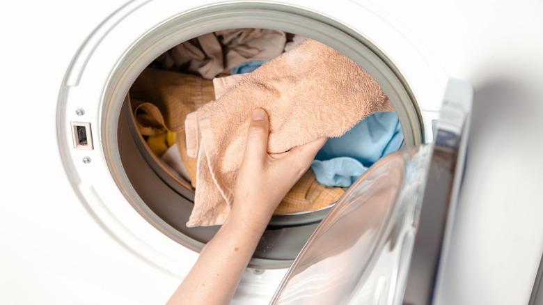 hand putting laundry into washing machine