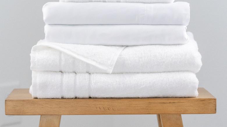 Stack of white sheets and towels on a wood bath stool