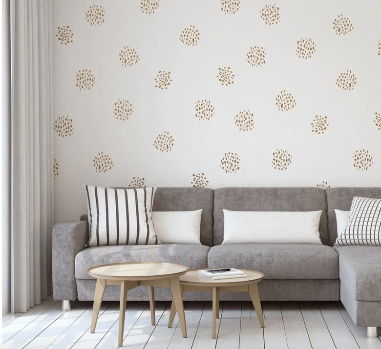 Living room with gray couch, small coffee tables, pillows, wall decals.