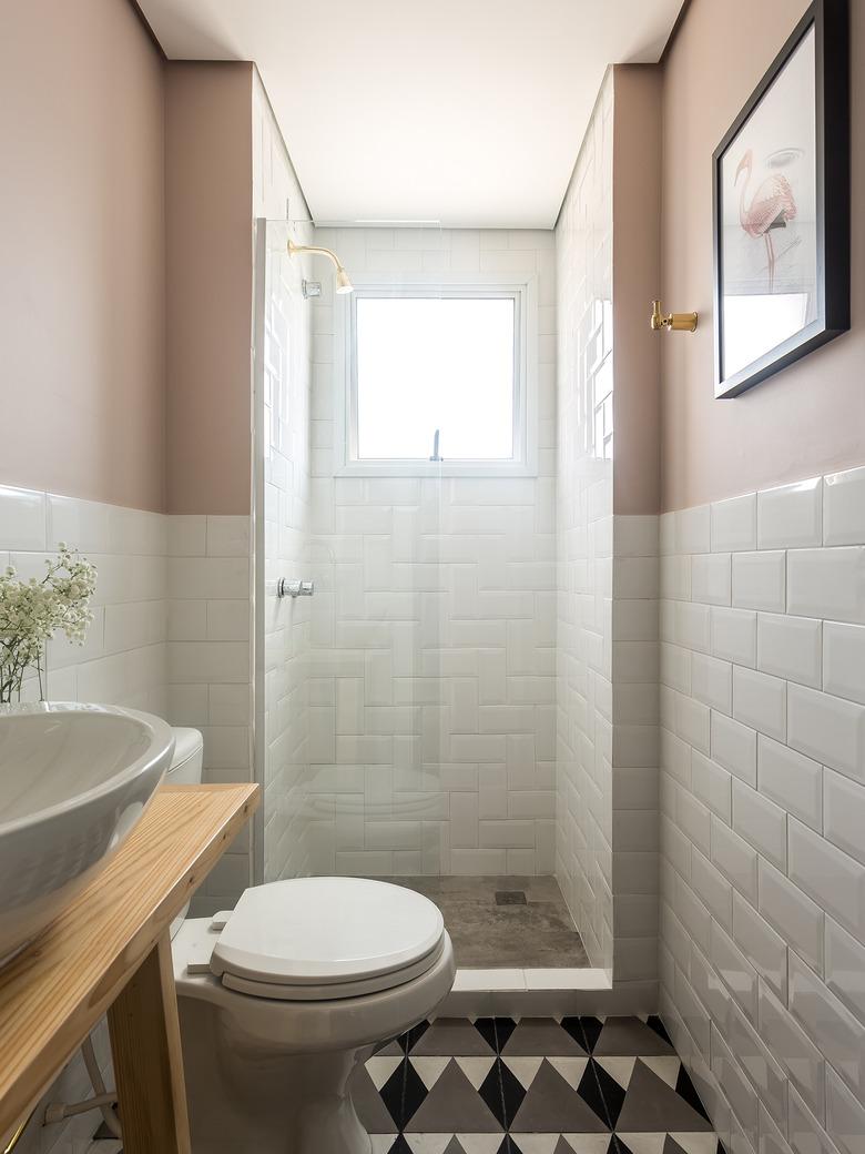 bathroom with white subway tile, dusty rose walls, and brass accents