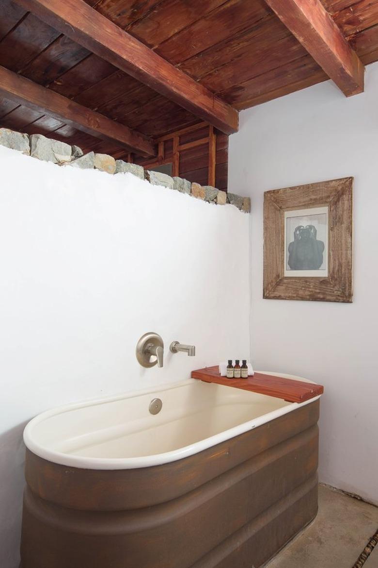 redwood open beamed ceiling in bathroom with horse trough bathtub and redwood bath caddy