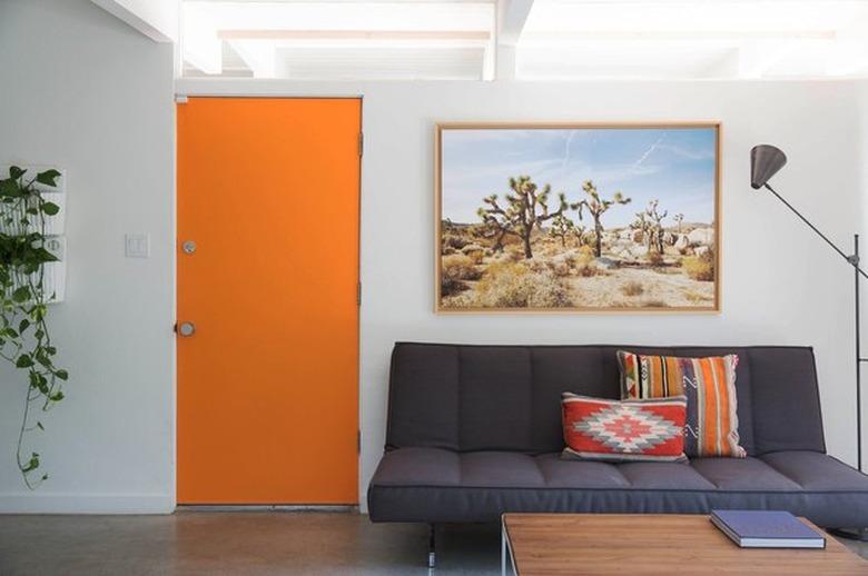 modern entryway living room with bright orange front door and midcentury style furniture