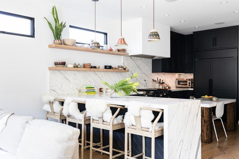 White walled kitchen with granite counters, white chairs, and dark gray cabinets