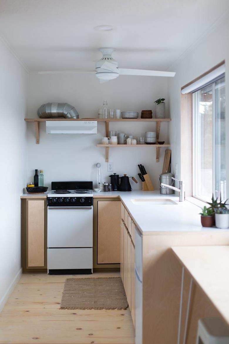 small well-organized kitchen with ceiling fan and large window