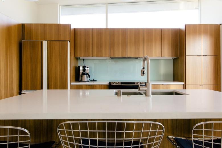 a large kitchen with many mid-century wood-fronted cabinets; the refigerator has a matching facade