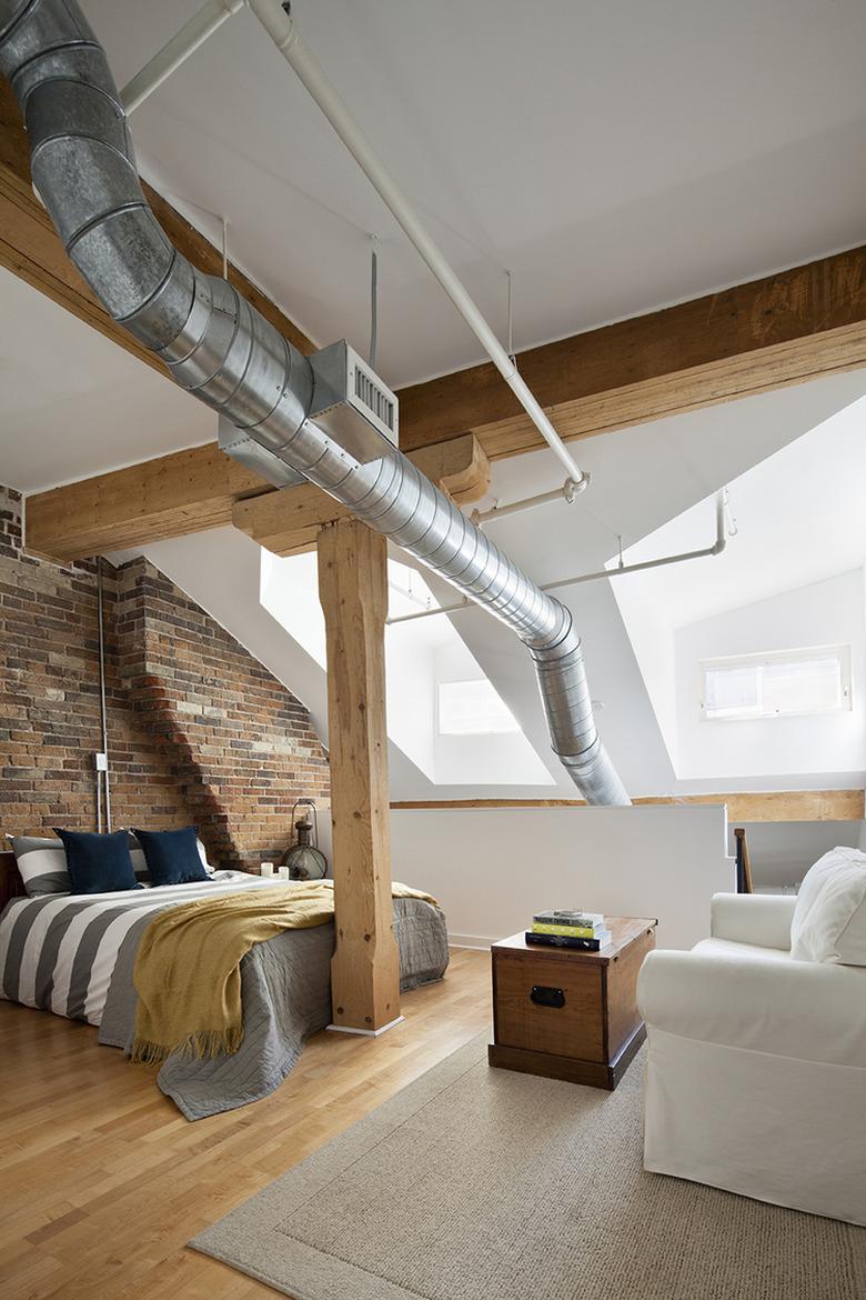 industrial bedroom with exposed ductwork and wood ceiling beams