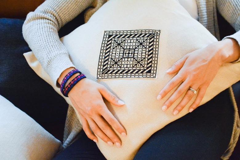 person holding white pillow with black pattern in the center