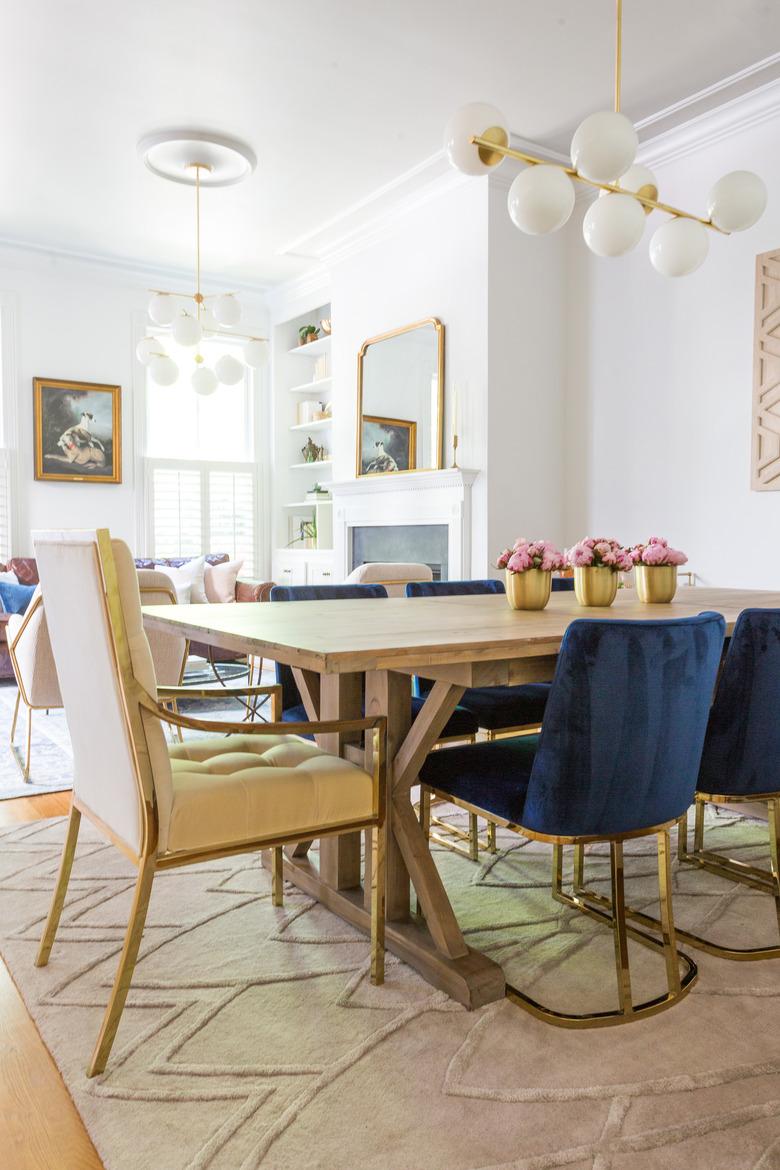 White and brass art deco dining room with velvet chairs and modern chandelier