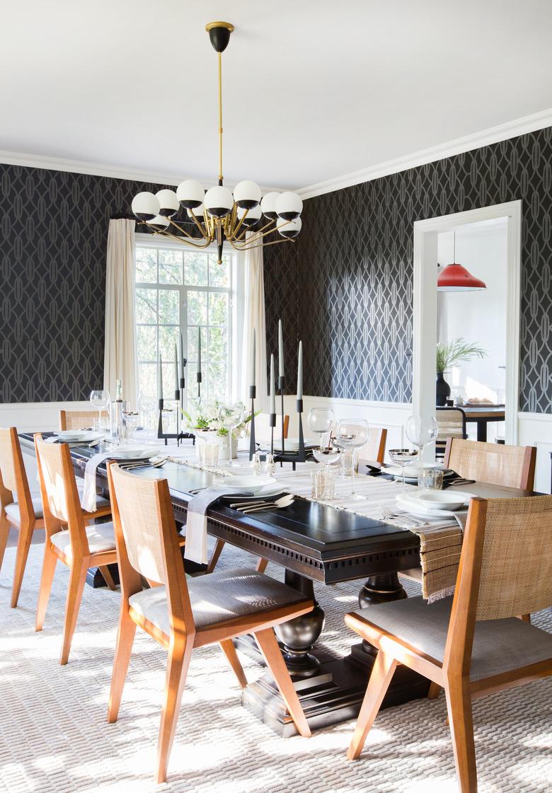 Black and brass art deco dining room with wood chairs and patterned wallpaper