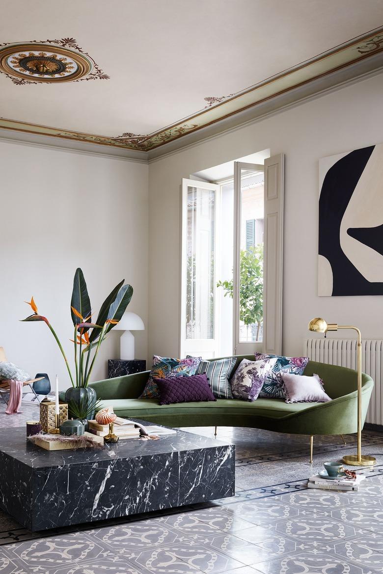 gray and white art deco living room with curved, green velvet sofa and large black marble coffee table