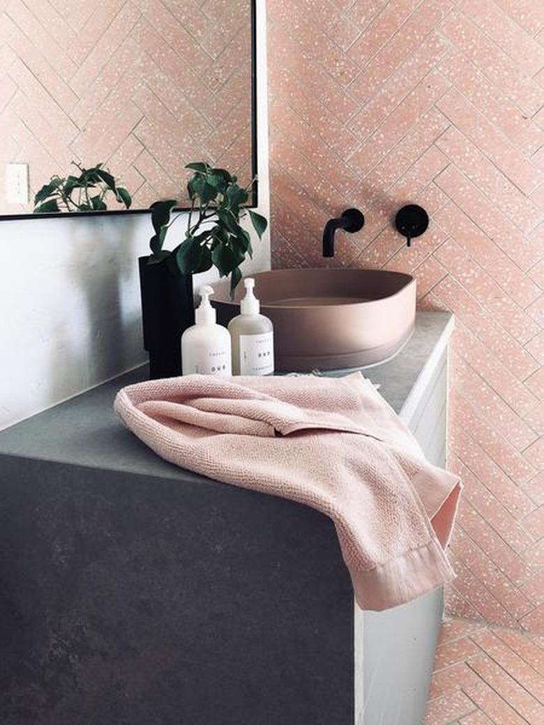 concrete bathroom countertop with vessel sink and pink wall and floor tile with wall-mounted faucet