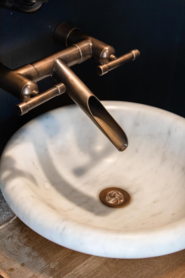 A white sink basin with an industrial style faucet