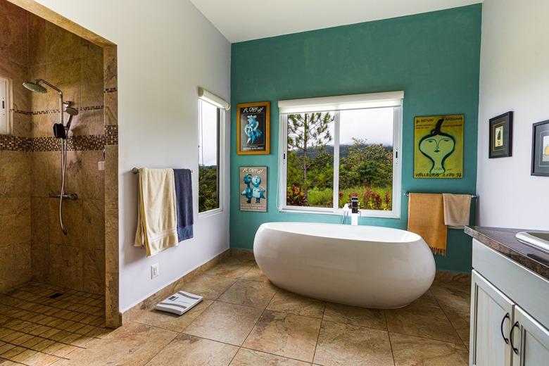 bathroom windows in bathroom with green accent wall and artwork framing window