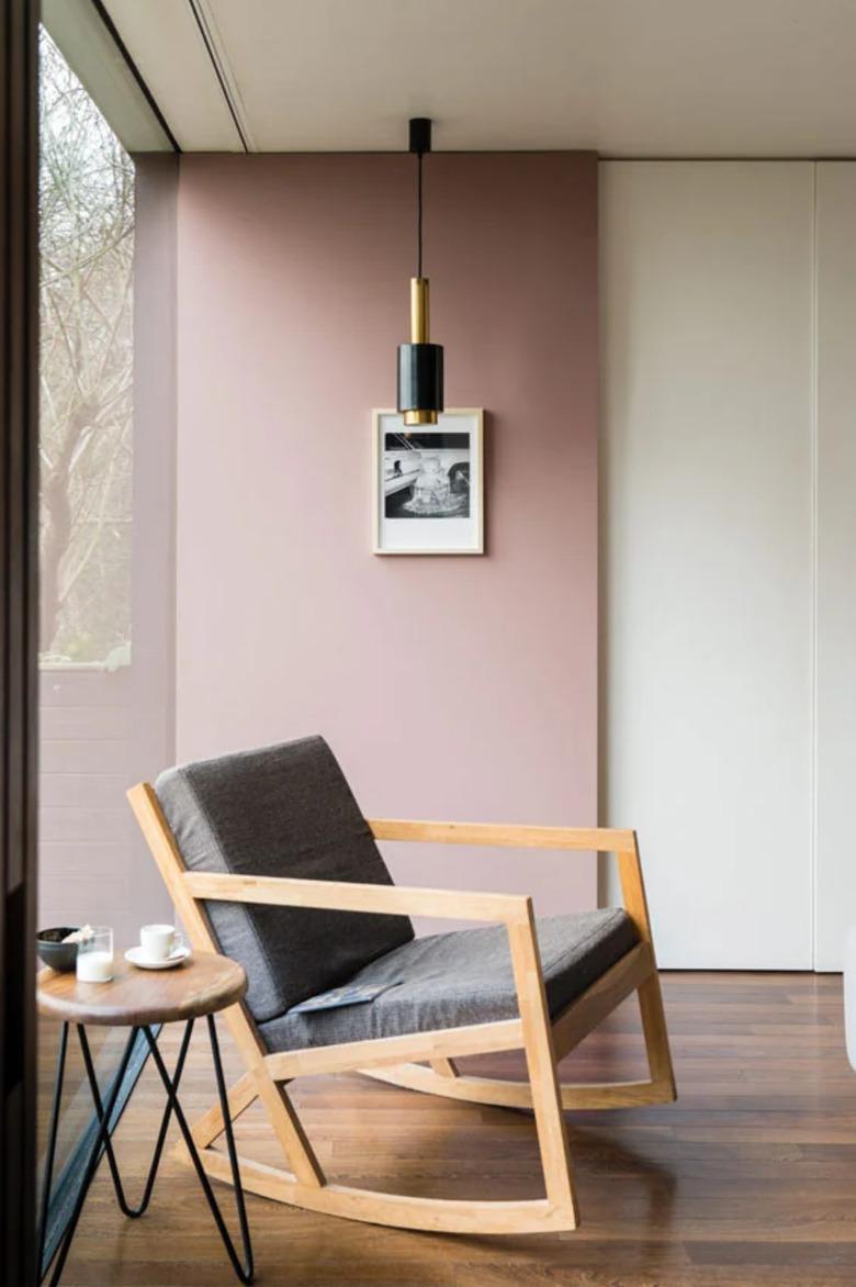 Bauhaus style room with pink accent wall, modern pendant light, and Bauhaus chair