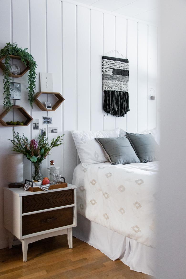 Bedroom with white walls, white bed, and plants