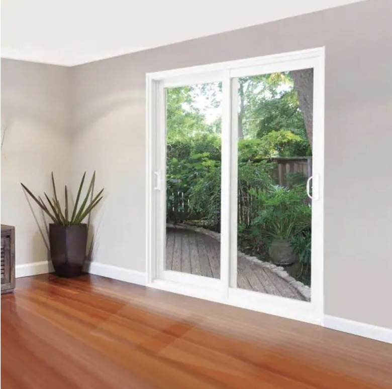 Sliding patio doors from the inside looking out. The room has hardwood floors and a plant in the corner.