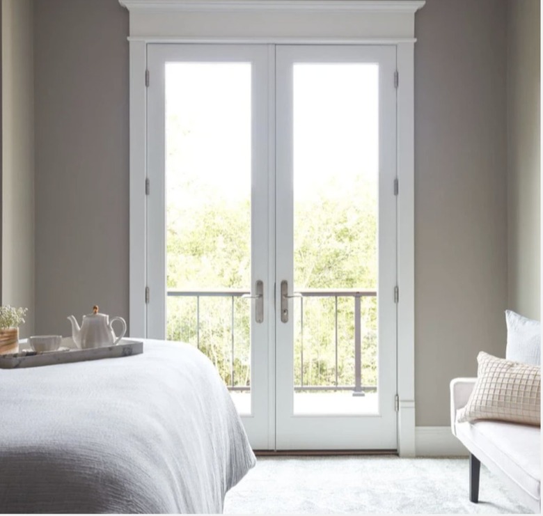 Image of patio doors looking our from a bedroom. Room has a bed with white bedding with a breakfast tray and white settee against the wall.