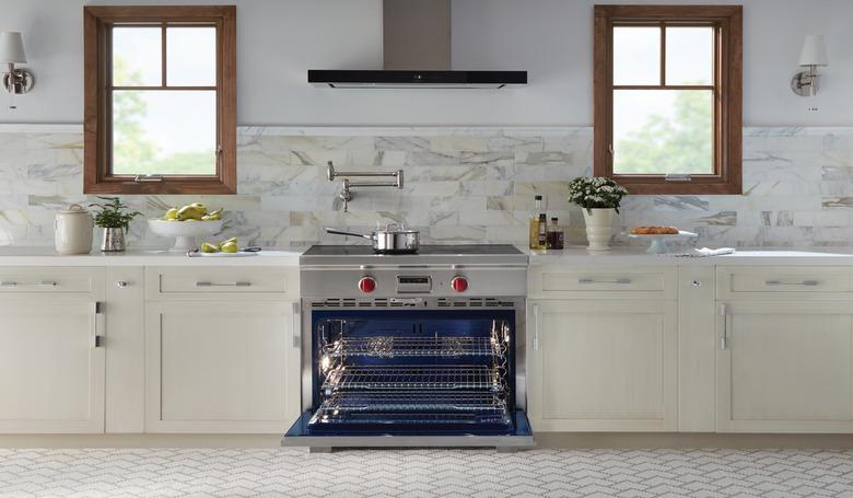 stove brand Wolf in a white kitchen with two windows and white countertops with wolf stove in the center