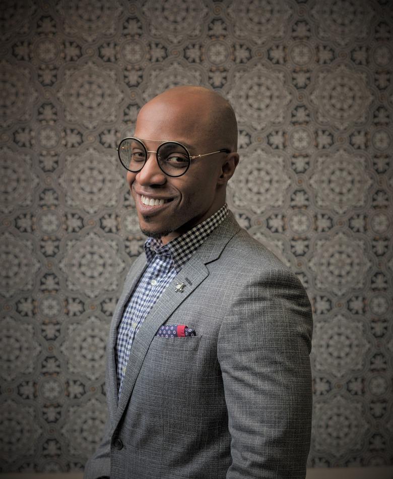 photo of designer corey damen jenkins standing in front of patterned wall