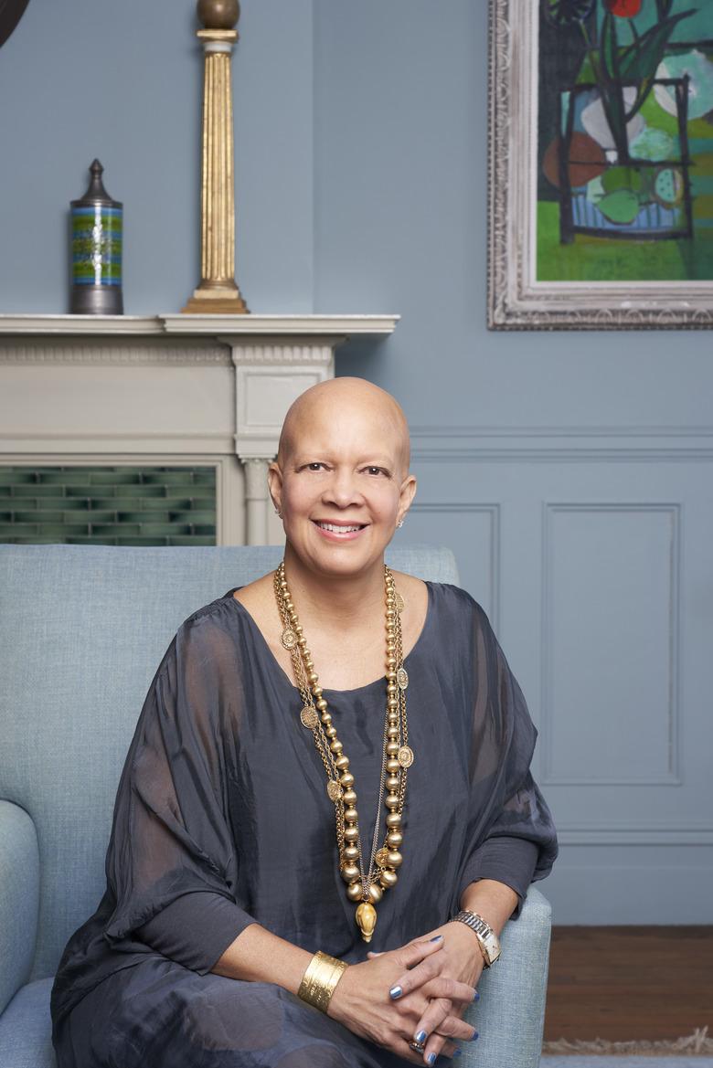 figure sitting in blue chair with fireplace in the background and blue walls