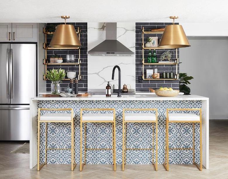 patterned blue kitchen island with white waterfall countertop and brass stools