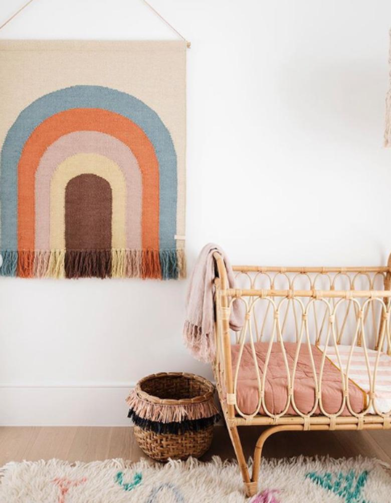 bohemian baby nursery idea with rainbow wall hanging and bentwood crib