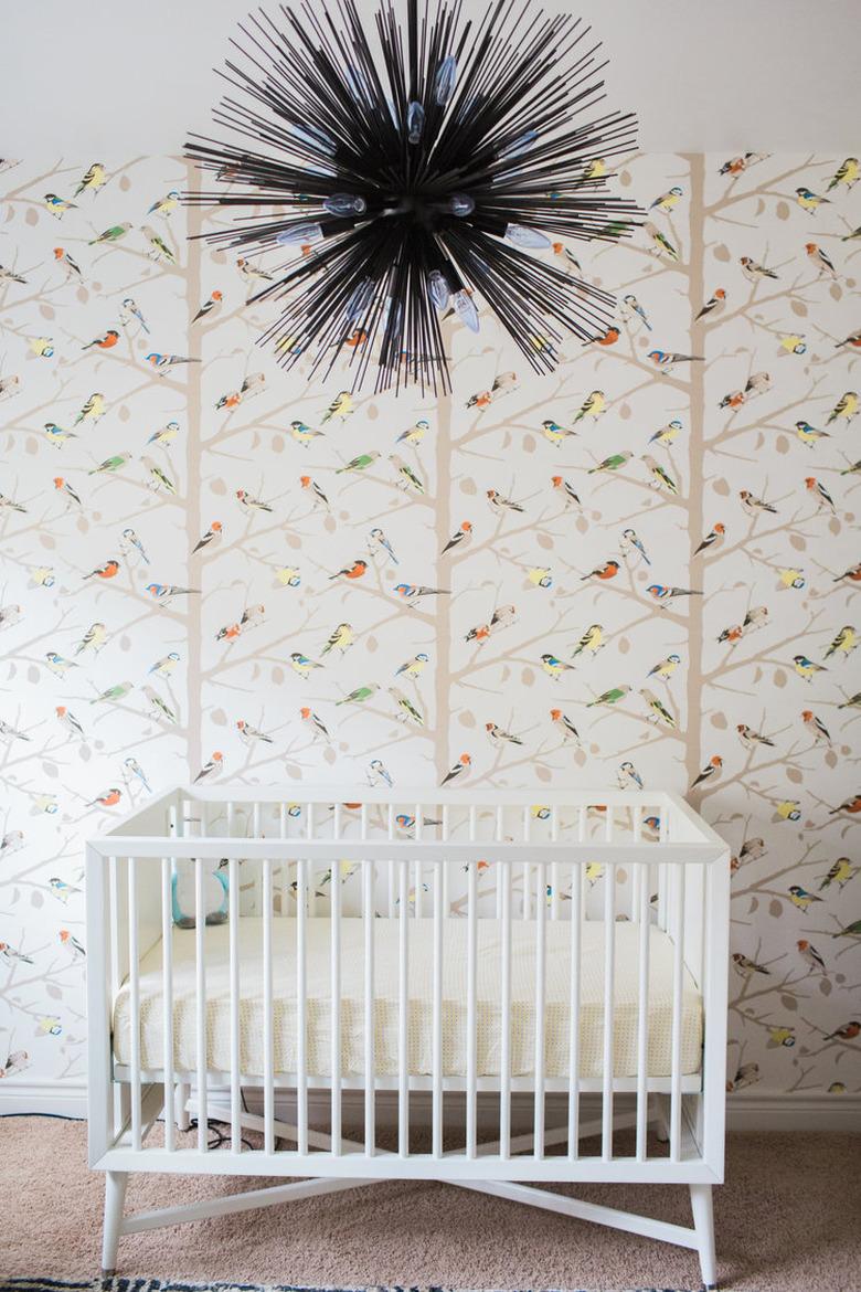 bohemian baby nursery idea with iron chandelier and parrot wallpaper