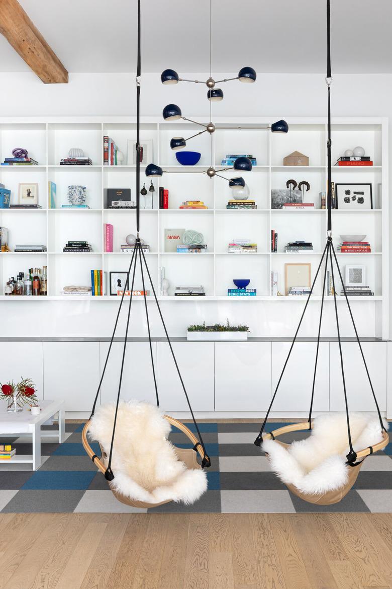 book storage in A modern bedroom with two ceiling-mounted swing chairs and bookshelves.