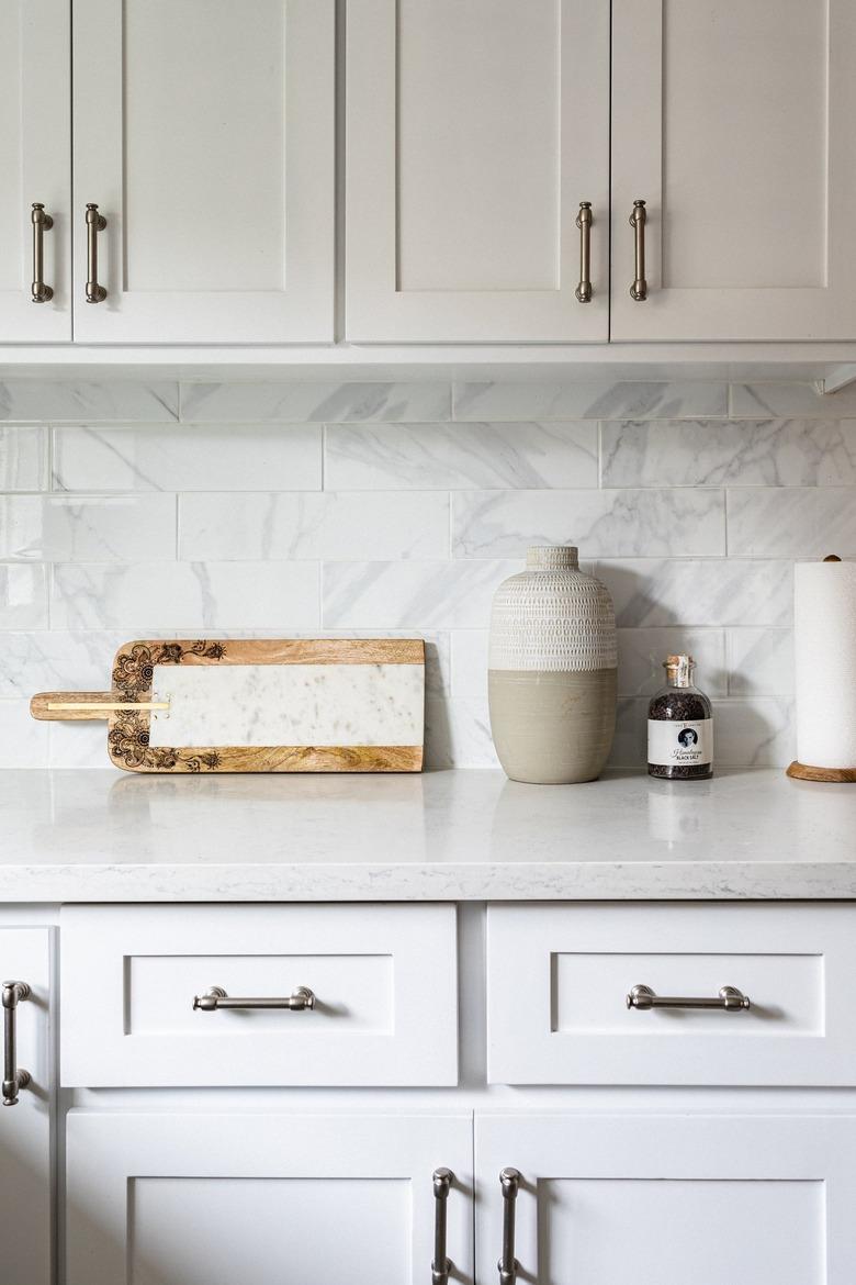 Minimalist kitchen with white cabinets and countertops and tile backsplash