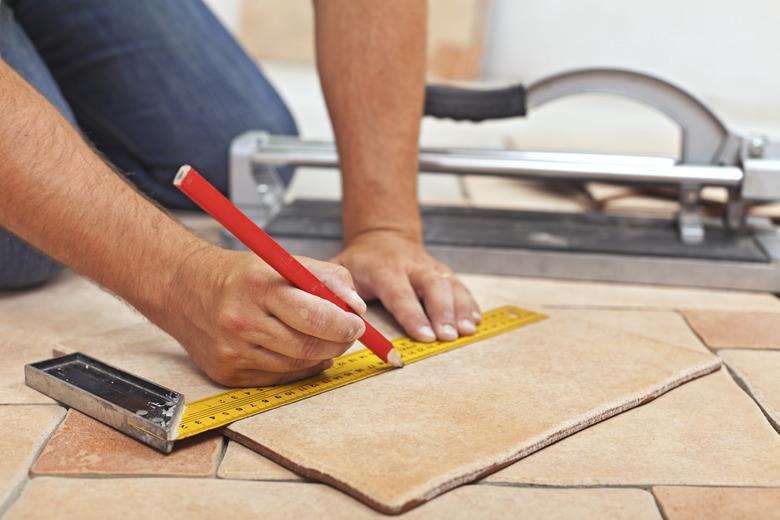 Laying ceramic floor tiles - man hands closeup