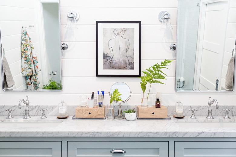 bathroom space with two mirrors and artwork in the middle