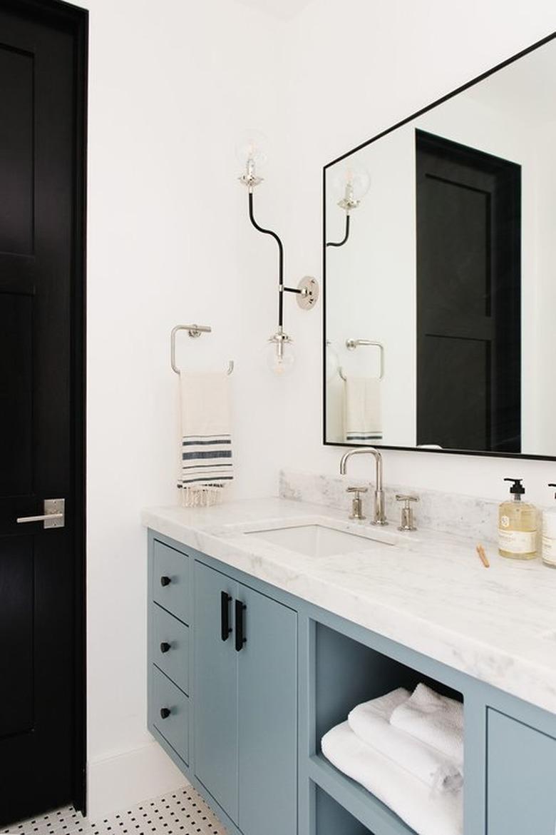 bathroom space with one large mirror and blue cabinets