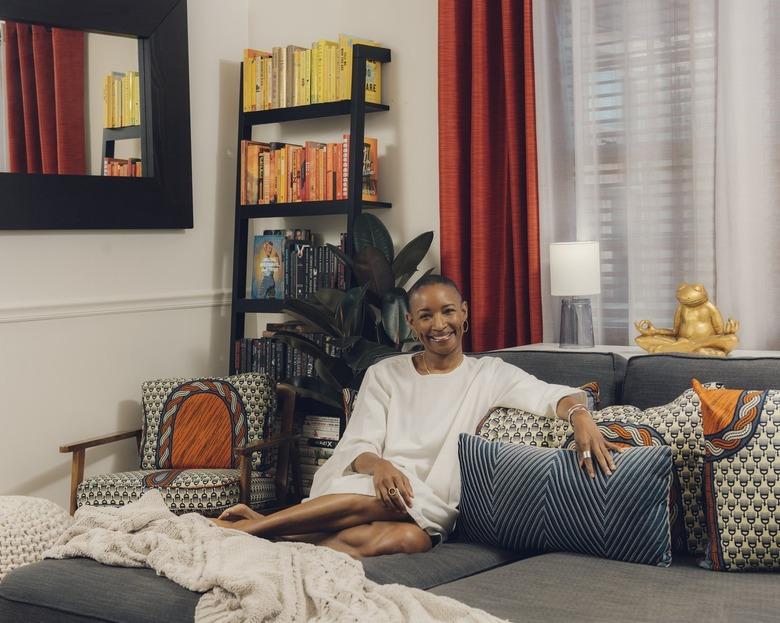 living room space with bookshelf and couch and woman sitting against couch