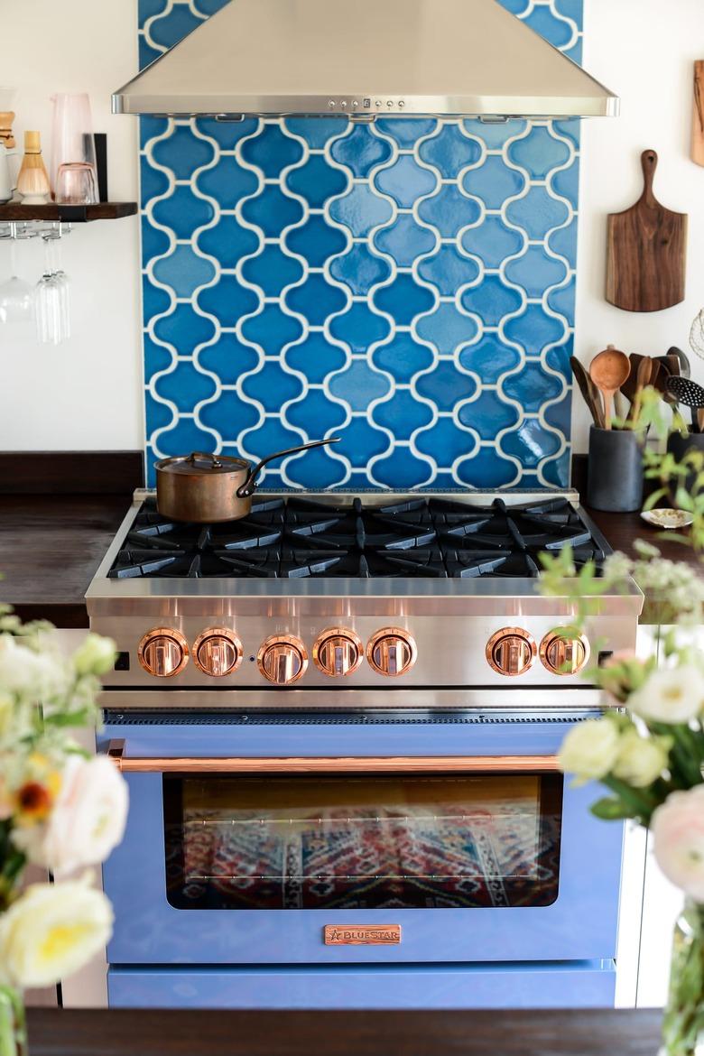 Dark blue coastal backsplash in fish scale shapes with blue stove