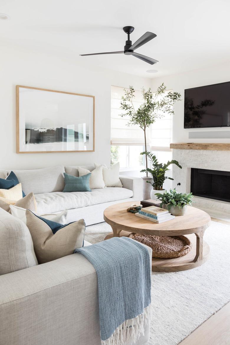 white living room with coastal fireplace white sofas and ceiling fan