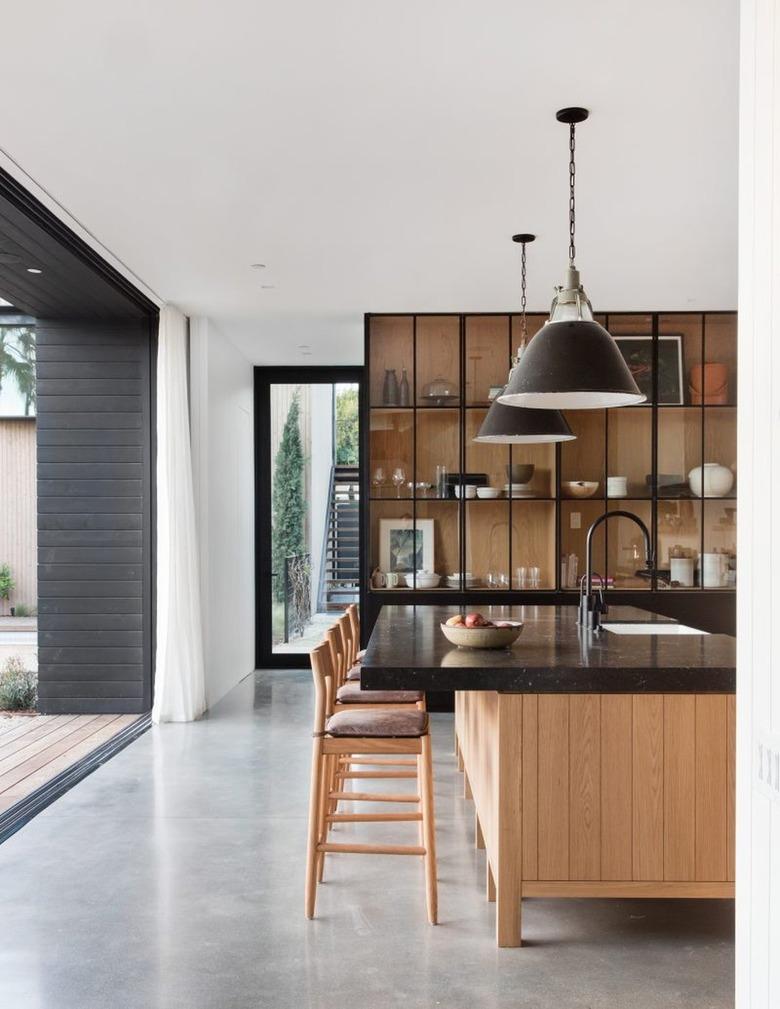 wood and black kitchen with glass front cabinets and concrete floors