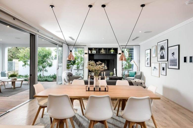 copper dining room light with pendants above wood table and white chairs