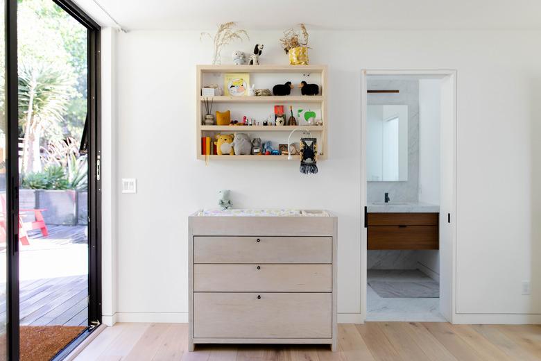 view of changing table, wall storage and hardwood floors