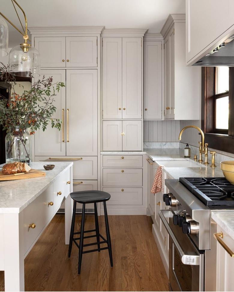 White craftsman kitchen cabinets with brass pulls and hardwood floor