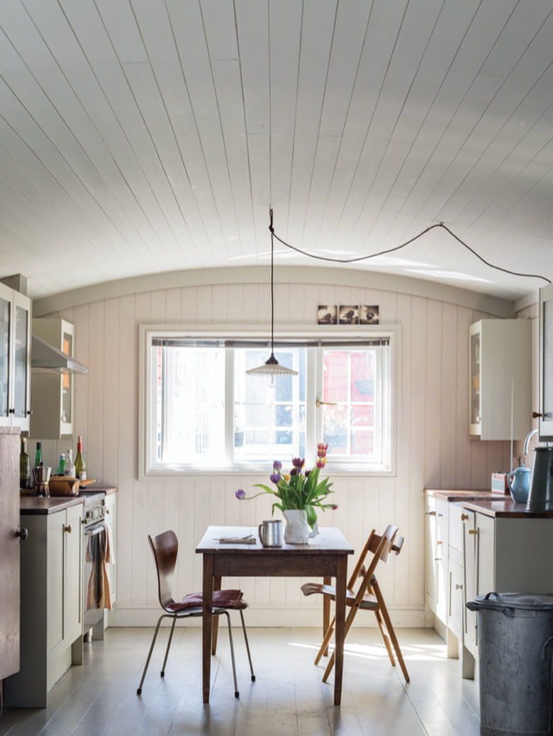 Kitchen with arched ceiling, pendant light, and dining table and chairs in middle