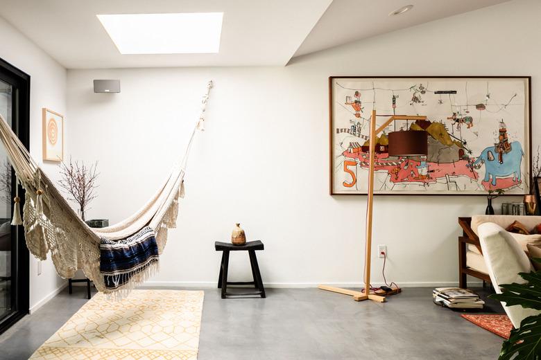 Hammock below skylight in artsy apartment with cement floors.