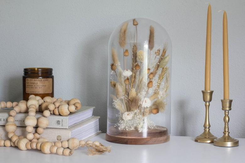 Cloche with dried plants and candlesticks with wood bead necklace